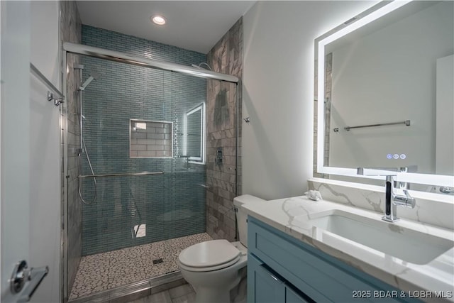 bathroom featuring toilet, vanity, and a shower with shower door