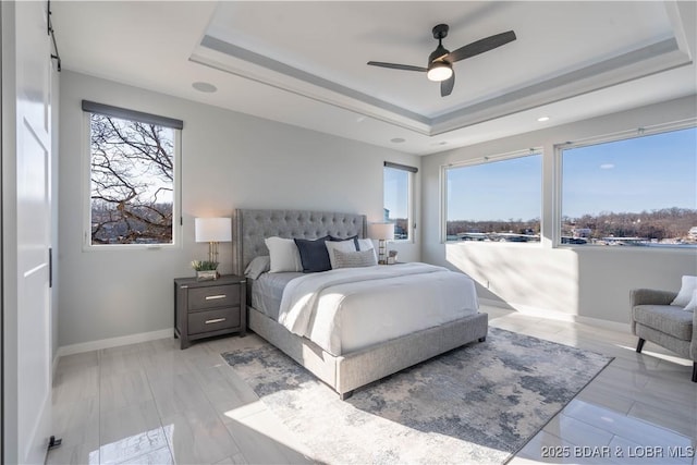 bedroom with ceiling fan and a tray ceiling