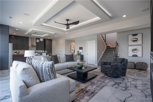 living room with ceiling fan and a tray ceiling