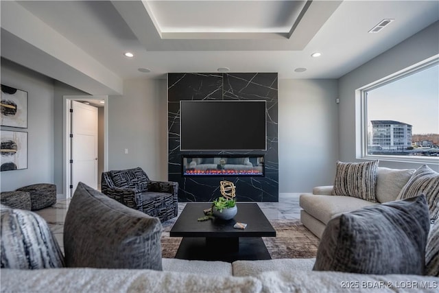 living room with a premium fireplace and a tray ceiling