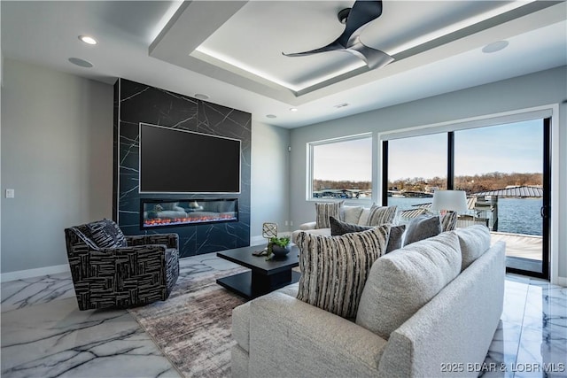 living room with ceiling fan, a fireplace, and a raised ceiling