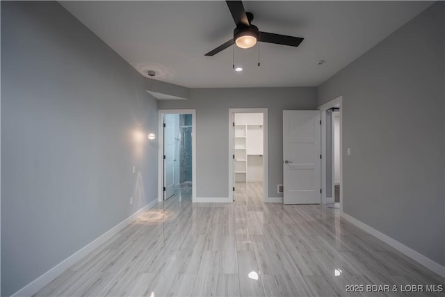 unfurnished bedroom with a spacious closet, light hardwood / wood-style floors, a closet, and ceiling fan