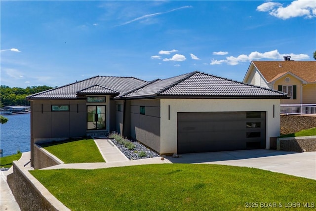 view of front of home with a garage, a front yard, and a water view