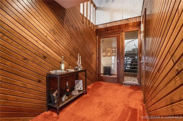 hall featuring wooden walls and carpet floors