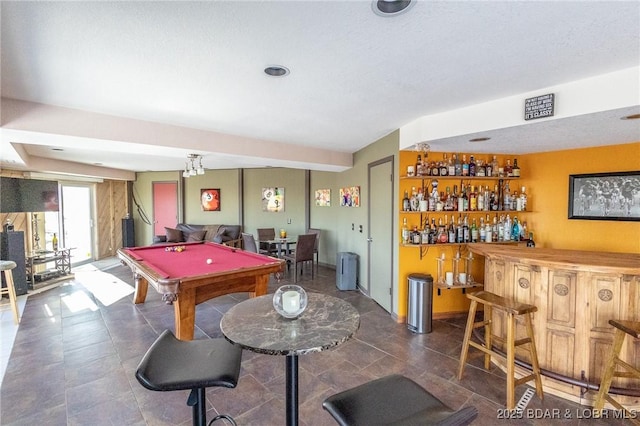 game room with pool table, a textured ceiling, and bar area