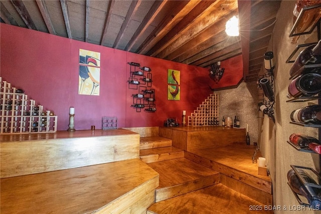 wine area featuring wood-type flooring and beamed ceiling