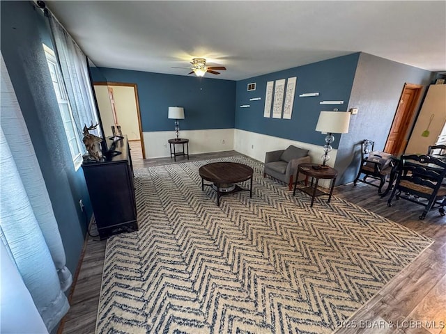 living area with visible vents, dark wood-type flooring, and a ceiling fan