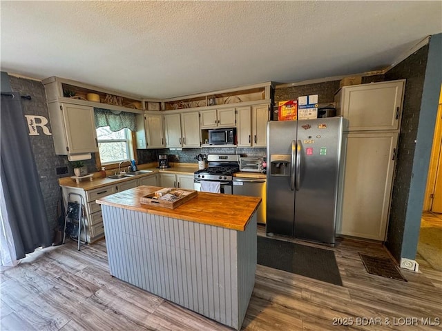 23731 Grant Rd, Barnett, MO 65011 - kitchen featuring appliances with stainless steel finishes, wood counters, light wood-style floors, a textured ceiling, and a kitchen island