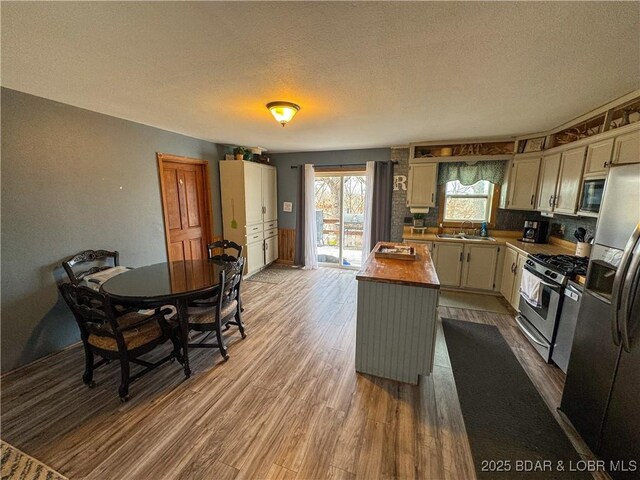 23731 Grant Rd, Barnett, MO 65011 - kitchen featuring appliances with stainless steel finishes, dark wood-style floors, a center island, a textured ceiling, and butcher block counters