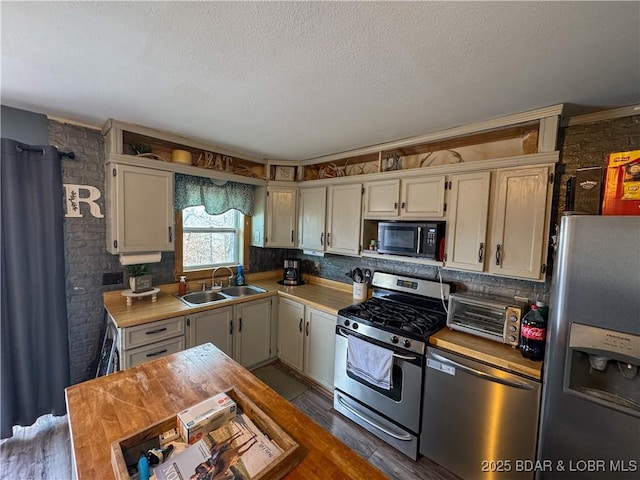 kitchen with appliances with stainless steel finishes, a toaster, light countertops, and a sink