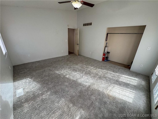 unfurnished bedroom featuring high vaulted ceiling, visible vents, ceiling fan, and carpet flooring