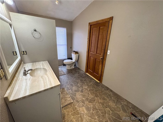 bathroom with vanity, lofted ceiling, and toilet