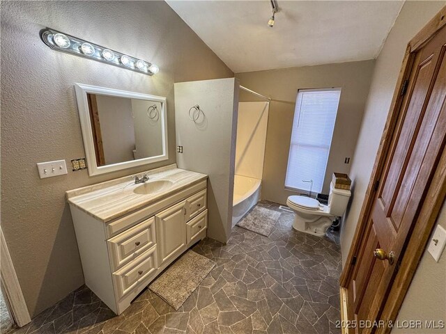 bathroom featuring toilet, stone finish flooring, vaulted ceiling, vanity, and  shower combination