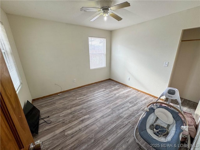 unfurnished bedroom with ceiling fan, wood finished floors, and baseboards