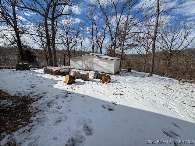 snowy yard with a garage, an outdoor structure, and a storage shed