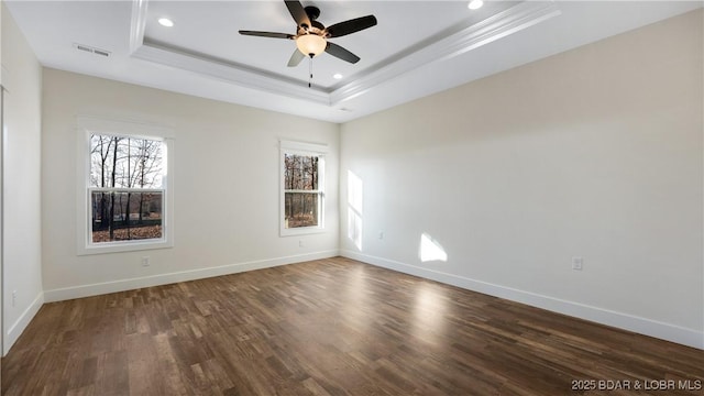 empty room with ceiling fan, dark hardwood / wood-style flooring, and a raised ceiling