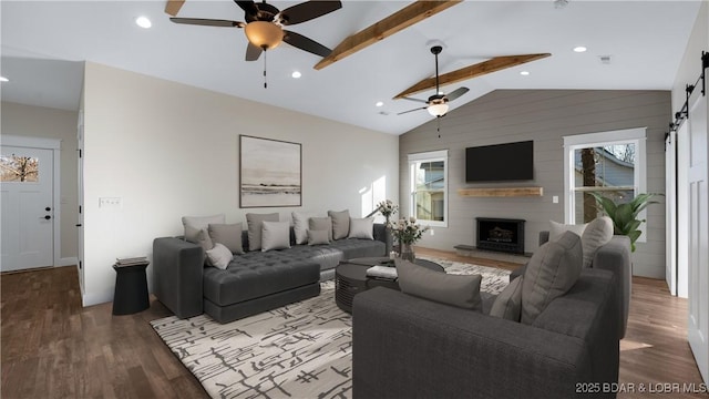 living room featuring a wealth of natural light, hardwood / wood-style floors, lofted ceiling with beams, and a barn door