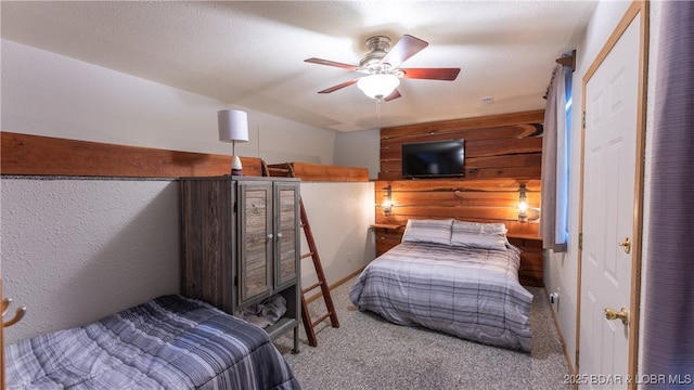 carpeted bedroom with ceiling fan and wood walls