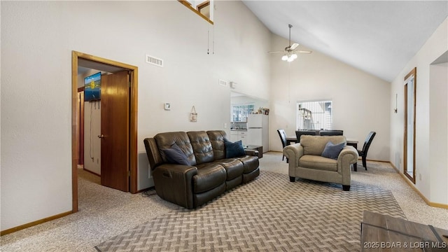 carpeted living room with ceiling fan and high vaulted ceiling