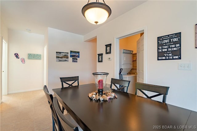 dining area featuring light tile patterned floors and stacked washer / drying machine