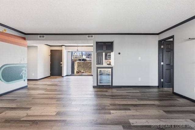 unfurnished living room with crown molding, dark hardwood / wood-style floors, and a textured ceiling