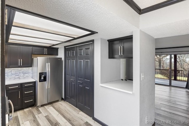 kitchen featuring range, stainless steel refrigerator with ice dispenser, ornamental molding, light hardwood / wood-style floors, and decorative backsplash