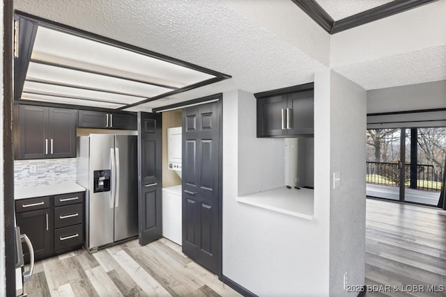 kitchen featuring range, light hardwood / wood-style flooring, ornamental molding, stainless steel fridge, and decorative backsplash