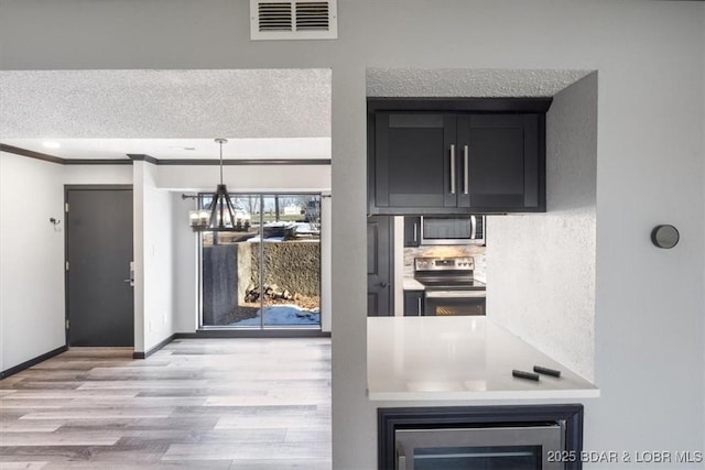 kitchen with crown molding, hanging light fixtures, stainless steel appliances, wine cooler, and a chandelier