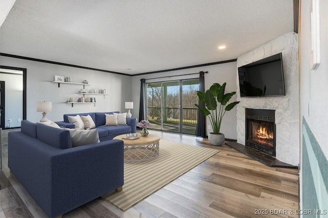 living room with crown molding, wood-type flooring, a fireplace, and a textured ceiling