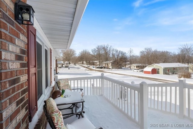 snow covered back of property with covered porch