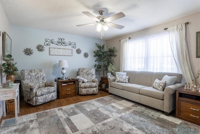 living room featuring ceiling fan, dark hardwood / wood-style flooring, and a textured ceiling