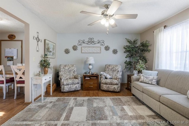 living room featuring ceiling fan, a textured ceiling, and hardwood / wood-style floors