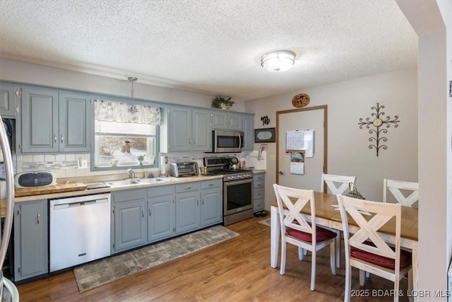 kitchen featuring light hardwood / wood-style floors, decorative backsplash, sink, a textured ceiling, and stainless steel appliances