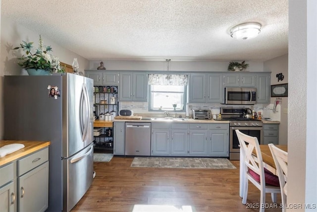 kitchen featuring a textured ceiling, appliances with stainless steel finishes, backsplash, and sink