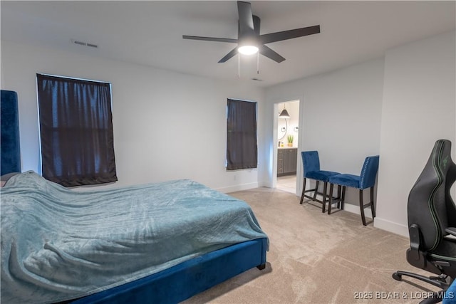 bedroom featuring ceiling fan, ensuite bath, and light carpet