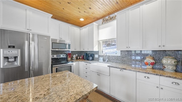 kitchen featuring light stone countertops, white cabinetry, stainless steel appliances, sink, and wooden ceiling