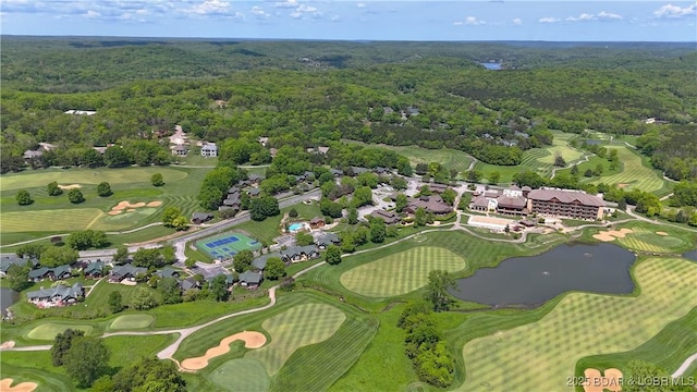 aerial view of property and surrounding area with a heavily wooded area and a local golf course
