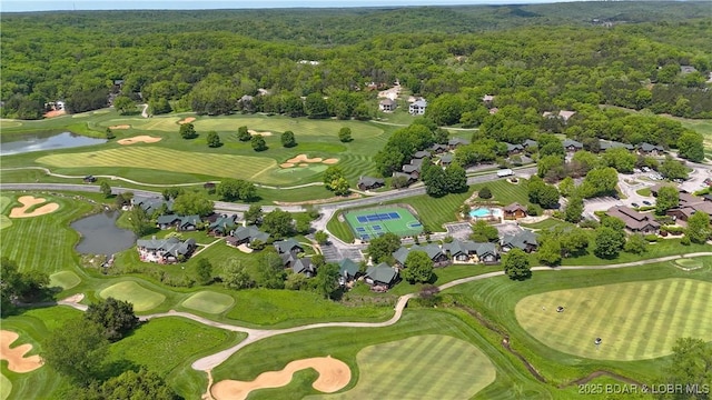 view of property location featuring a forest, a nearby body of water, and a golf club