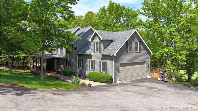 view of front of house featuring driveway, a garage, and a shingled roof