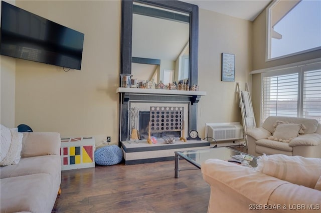 living room featuring a wall unit AC, a fireplace with raised hearth, and dark wood-style flooring