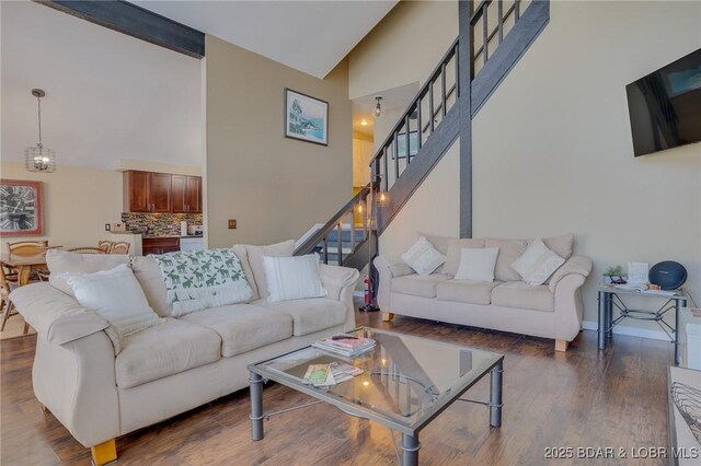 living room featuring a notable chandelier, dark wood-type flooring, beam ceiling, and high vaulted ceiling