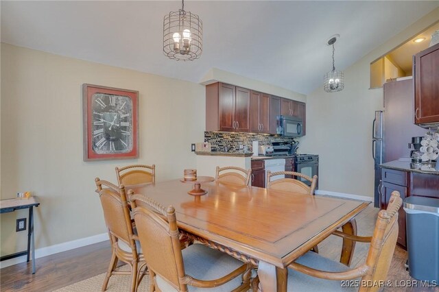 dining space featuring hardwood / wood-style floors, lofted ceiling, and a notable chandelier