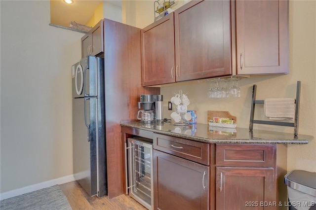 kitchen featuring black fridge, wine cooler, stone countertops, and light wood-type flooring