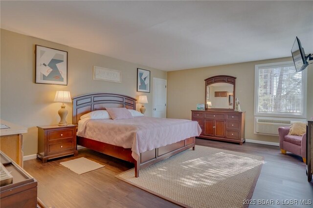 bedroom with an AC wall unit and wood-type flooring