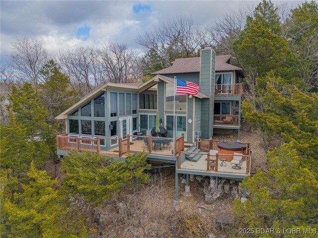 rear view of property with a deck and a hot tub