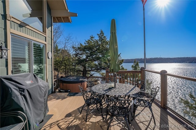 view of patio / terrace featuring a grill, a hot tub, and a deck with water view