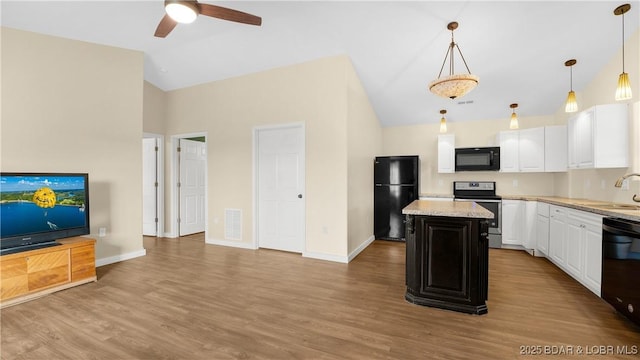 kitchen with a kitchen island, black appliances, light stone countertops, and pendant lighting