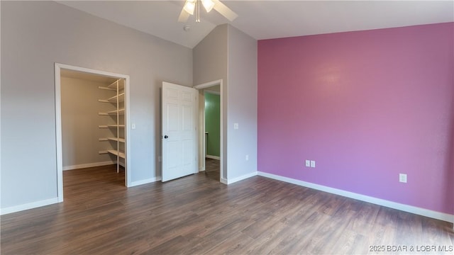 unfurnished bedroom featuring ceiling fan, high vaulted ceiling, a walk in closet, a closet, and dark hardwood / wood-style flooring