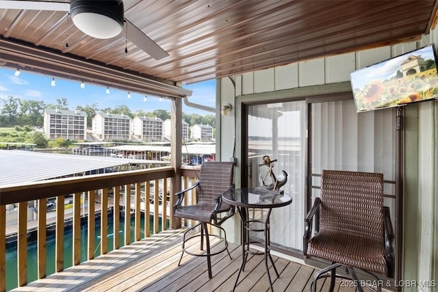 wooden deck with ceiling fan and a water view