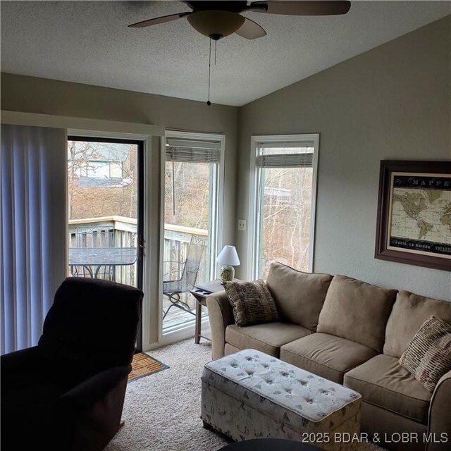 living room with light carpet, ceiling fan, vaulted ceiling, and a textured ceiling